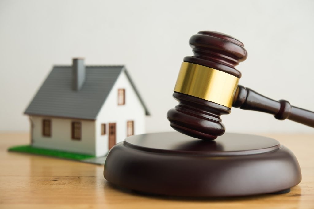 Gavel on table beside a small house model.