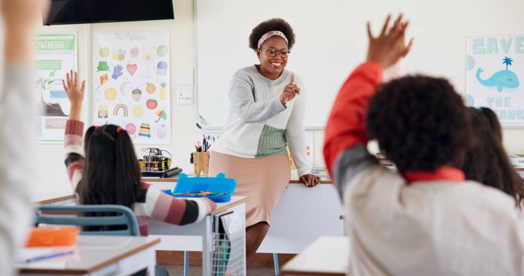 Smiling teacher calling on students during a classroom lesson.