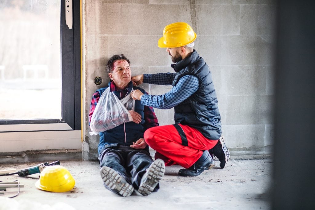 Man with arm injury being assisted by coworker.