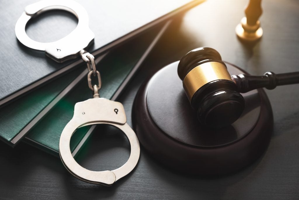 Handcuffs and gavel on a table with files.