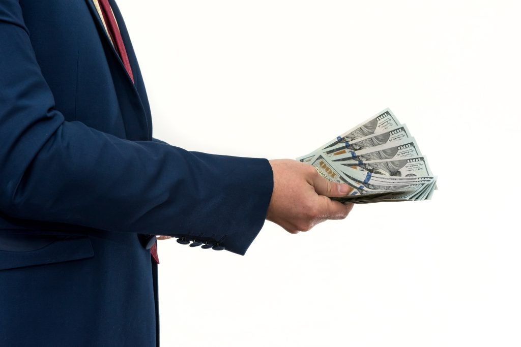 Man holding cash representing financial factors determining alimony eligibility.