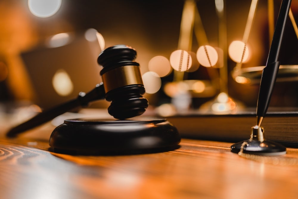 Judge's gavel and scales rest on a wooden table.