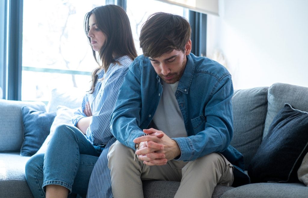 Couple on sofa looking upset.
