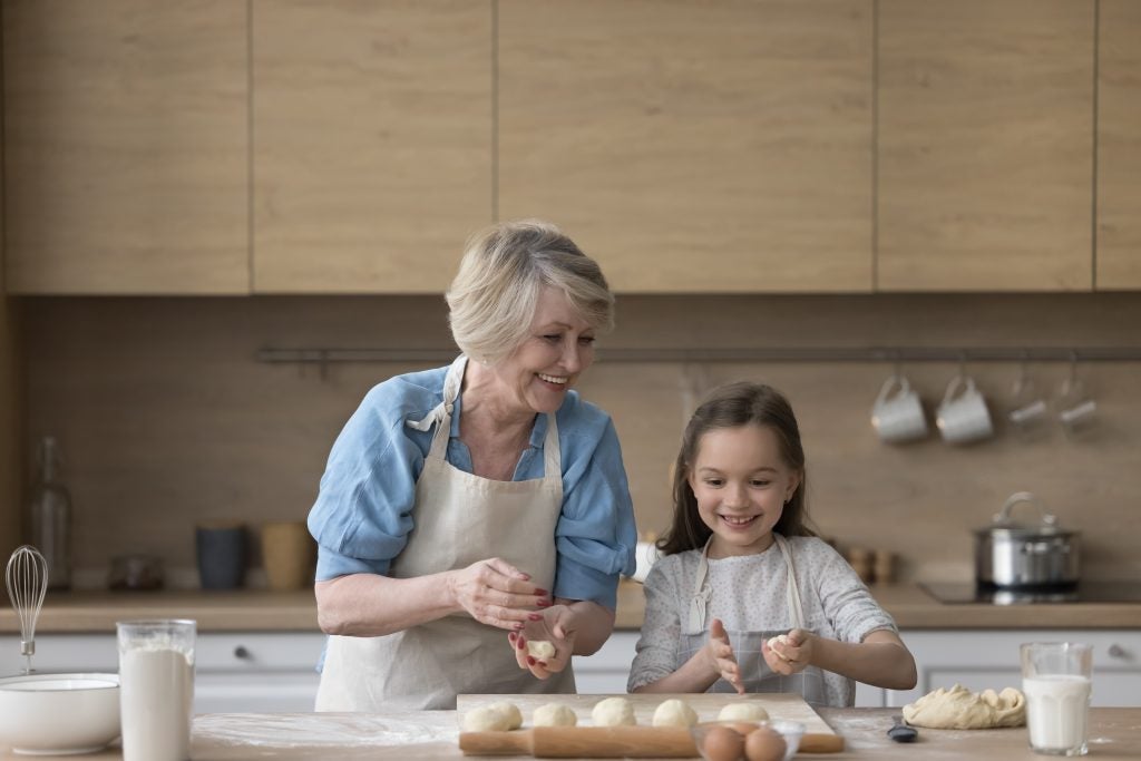 Grandmother helping granddaughter bake in the kitchen.