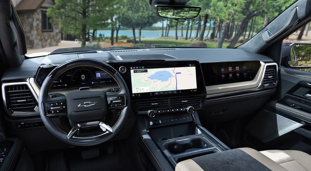 The front interior of a 2027 Chevy Silverado 1500 with infotainment and passenger screens.