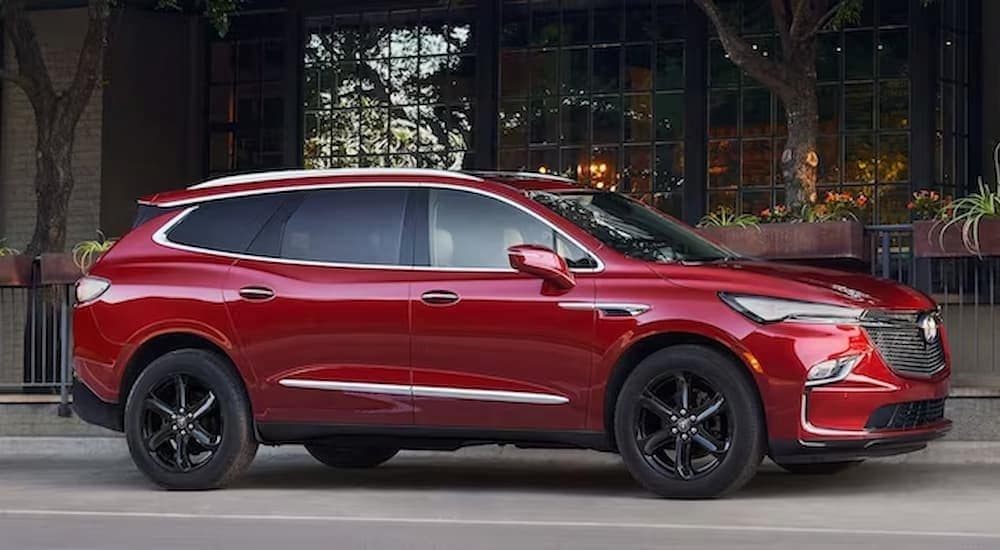 A red 2023 Buick Enclave is shown parked near flowers.