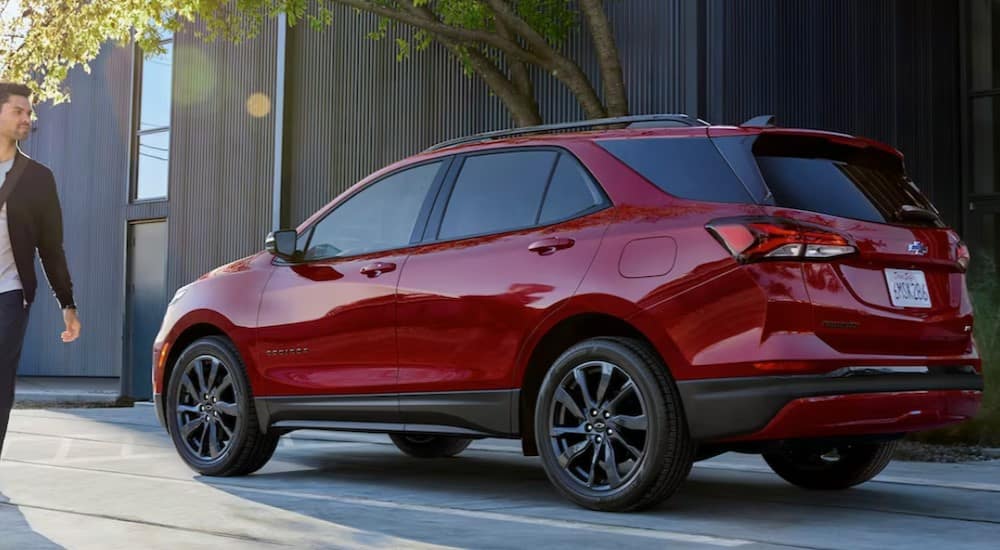 A red 2024 Chevy Equinox is shown parked near a building and a tree.