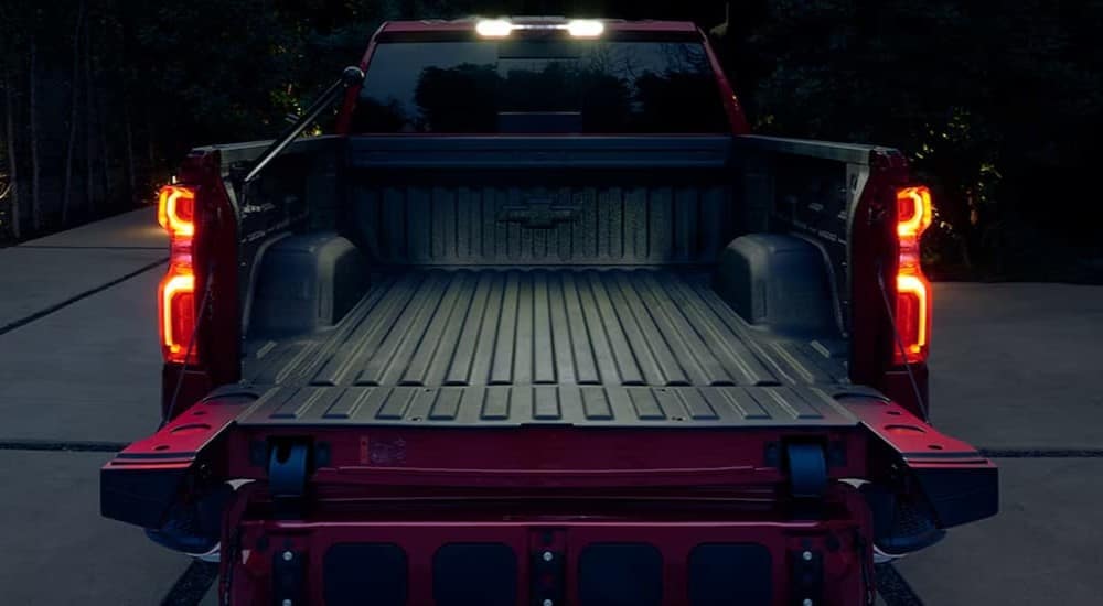 A red 2024 Chevy Silverado 1500 is shown with its tailgate open.