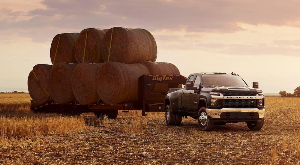 A black 2021 Chevy Silverado 3500 HD is shown from the front while towing hay bales.