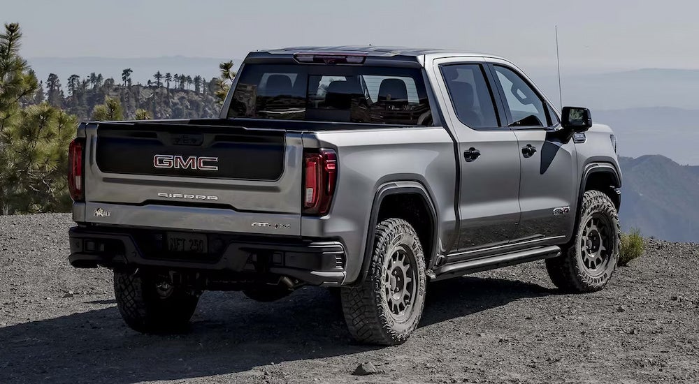 Rear view of a silver 2024 GMC Sierra 1500 AT4X parked on a mountain overlook.