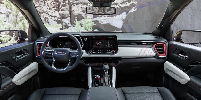 Driver's view of GMC Canyon interior with digital dashboard, large touchscreen, and rugged trim accents.