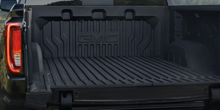 Open tailgate showing an empty, lined GMC truck bed with bold textured paneling.