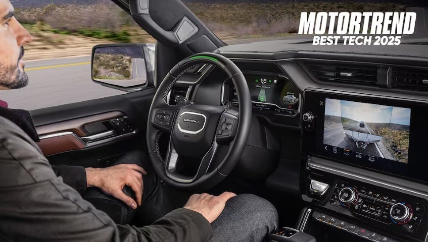 Driver using hands-free driving in a GMC Denali; digital screen shows trailer camera view with “MotorTrend Best Tech 2025” badge.