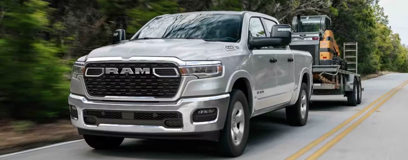 A silver 2026 Ram 1500 towing a trailer.