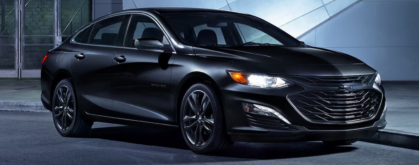 A black 2024 Chevy Malibu parked at night.