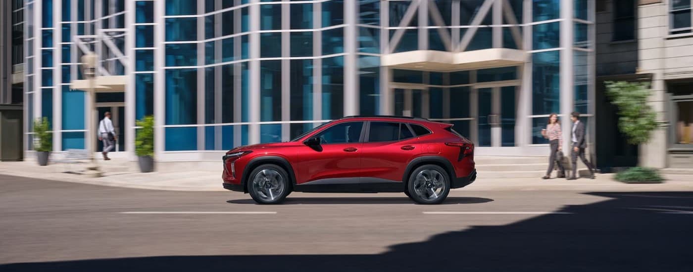 A red 2024 Chevy Trax driving in a city.