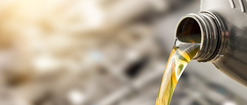 Motor oil pouring from a bottle into an engine.