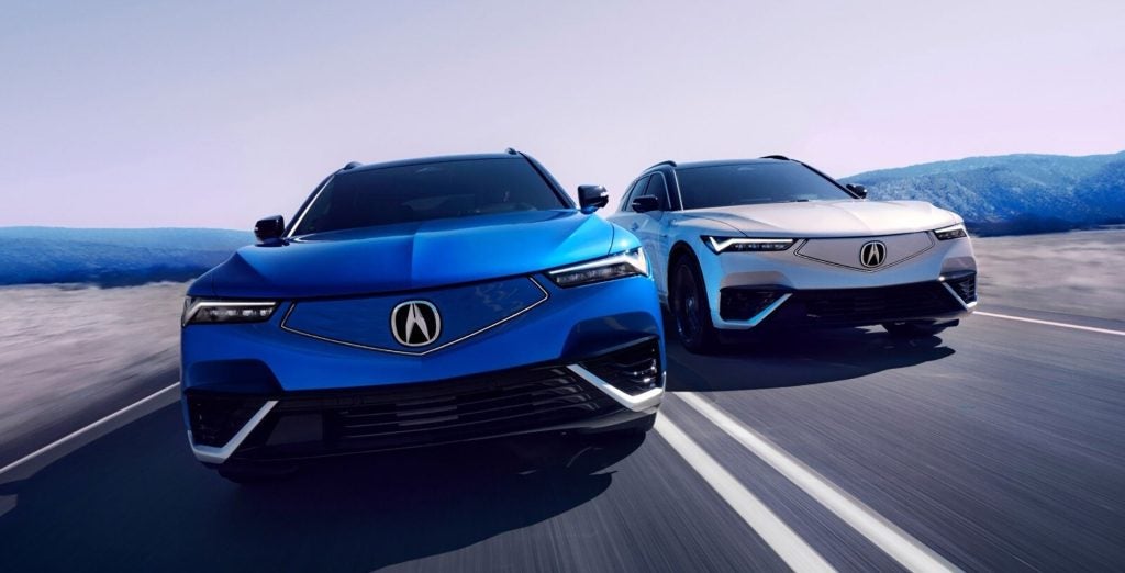 Two Acura SUVs driving side by side on a highway with motion blur and open landscape background.