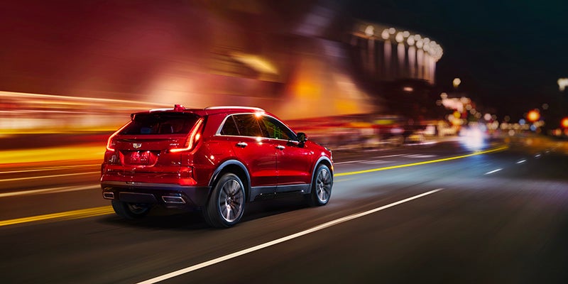 Cadillac XT4 driving fast on road at night.