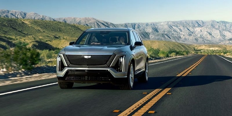 2026 Cadillac SUV driving on a scenic mountain road.