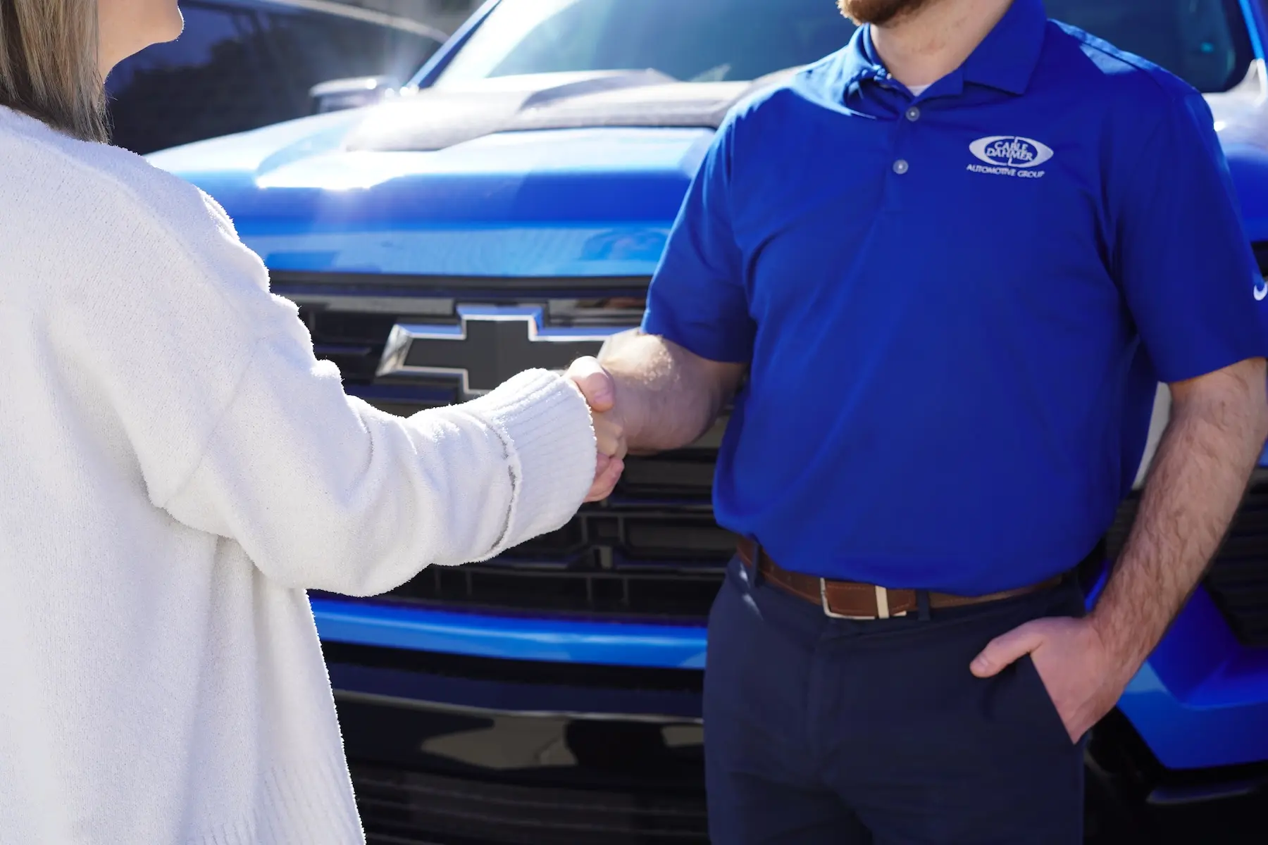 Customer shaking hands with a Cable Dahmer representative in front of a blue Chevrolet truck.