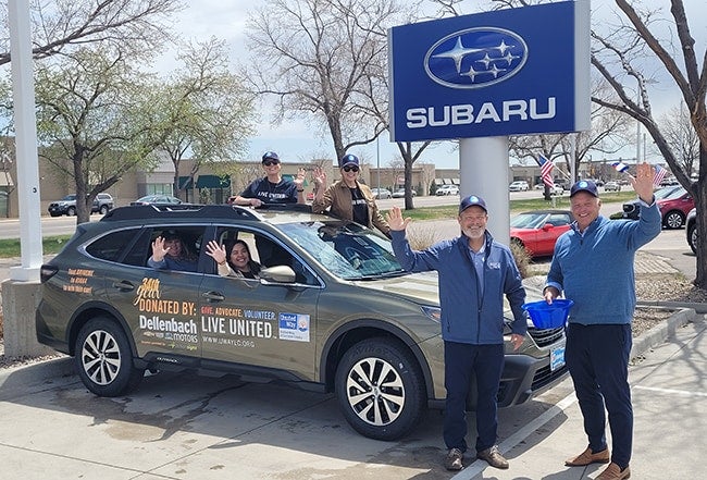 People waving around a Subaru Outback car