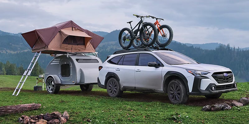 Subaru Outback towing camper in field