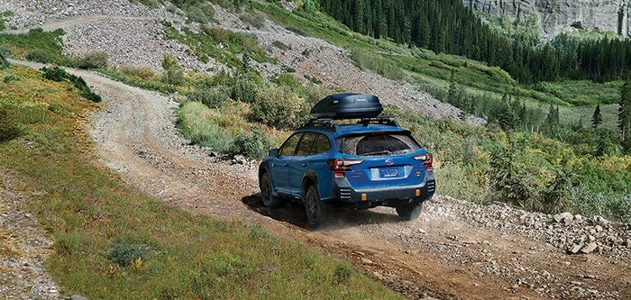 Subaru Outback driving through a forest stream