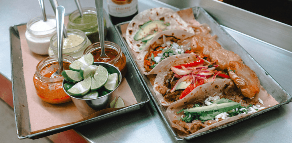 tacos and sauces in metal trays