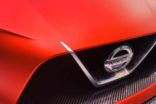 Up close photo of the front logo on a red Nissan Kicks vehicle