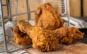 Three pieces of fried chicken sitting in a frying pan on a table