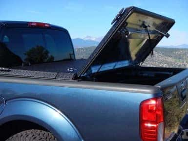 Side photo of a 2022 Nissan Frontier with the truck bed cover halfway open