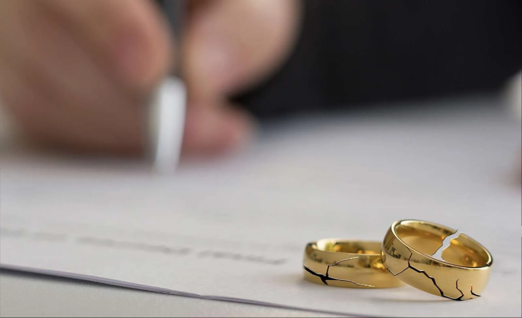 cracked wedding rings on top of divorce papers signaling summary dissolution