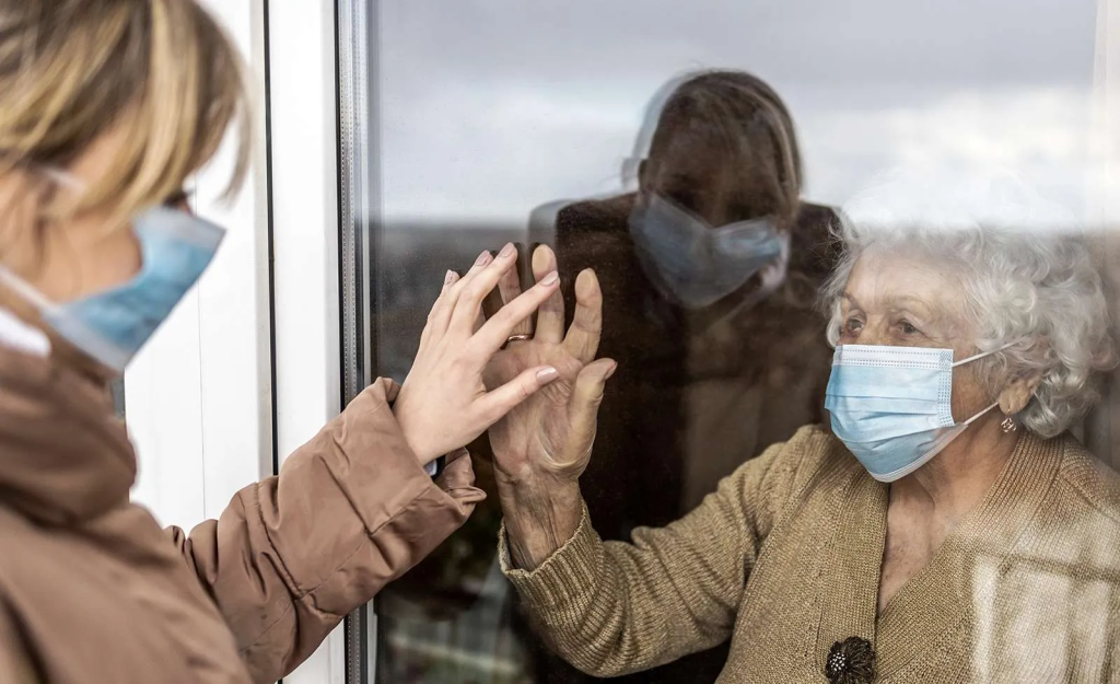 old woman and daughter touching hands through a pane of glass after isolation - anti-isolation restraining order reverse isolation
