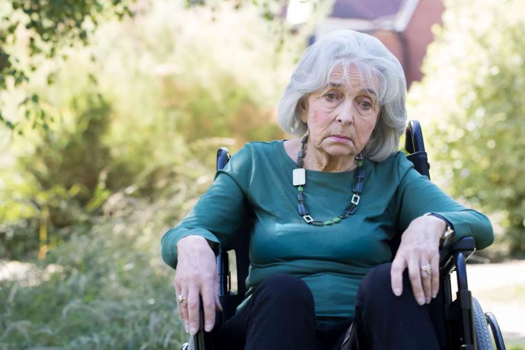 anciana mayor sentada sola en silla de ruedas en hogar de ancianos por negligencia 