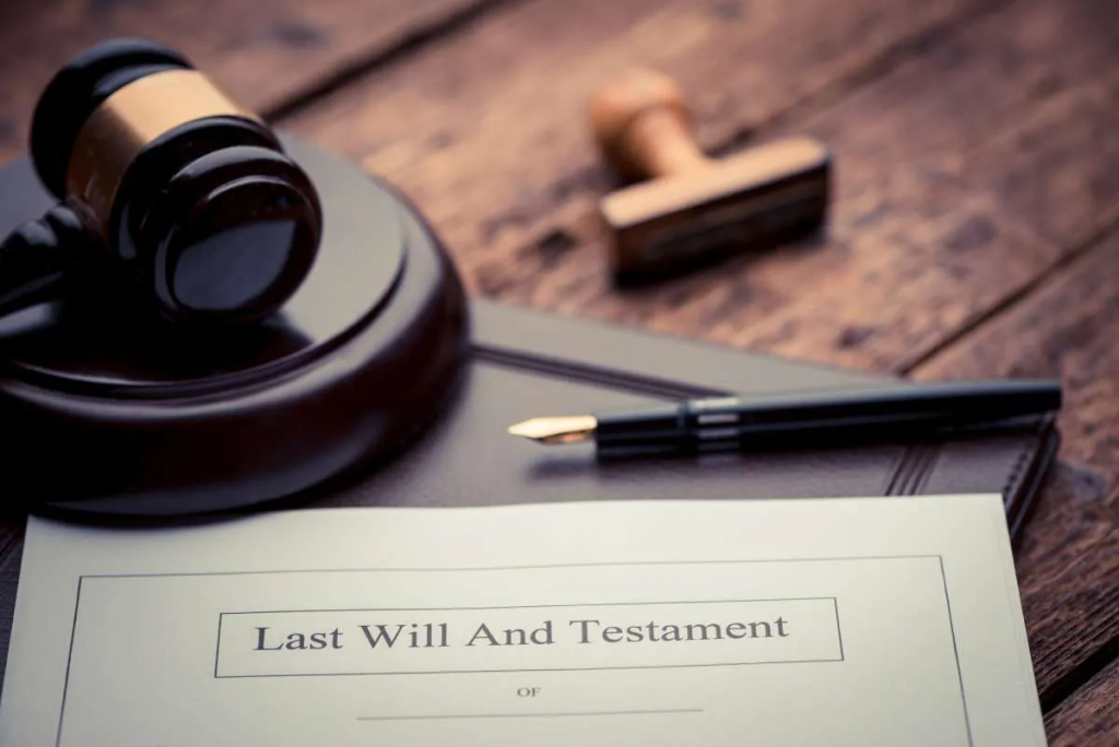 Close-up of a “Last Will and Testament” document on a wooden desk alongside a judge’s gavel, a pen