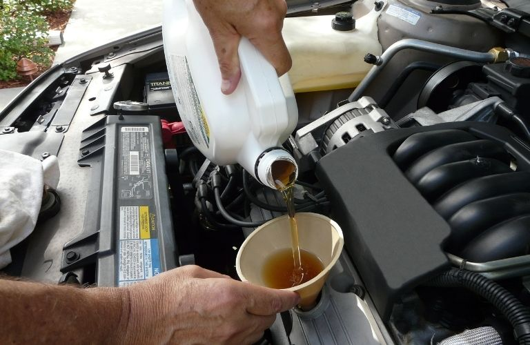 technician changing oil in a car