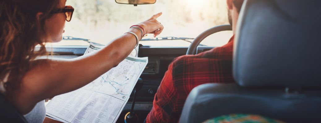 a couple in a car reading a map