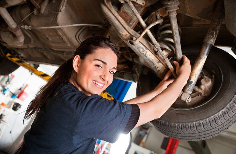 a woman working under the hood of a car