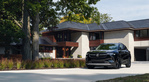 A 2023 Buick Enclave parked in front of a residential house.