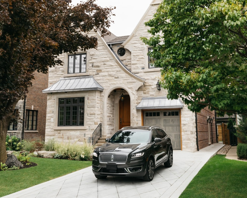 black luxury sedan parked in the driveway of a modern home.