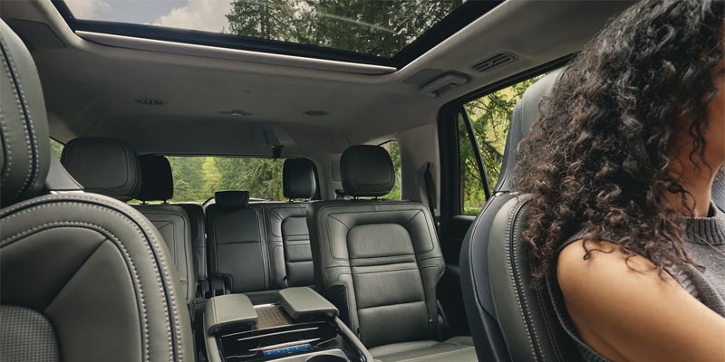 View of a car's three-row seating and panoramic sunroof from the driver's side.