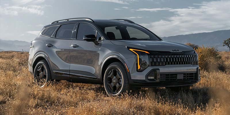 A Kia SUV in a field, displaying its modern design and sleek front grille.
