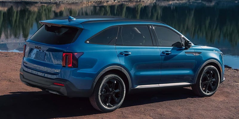 Blue Kia Sorento Hybrid SUV parked by lake