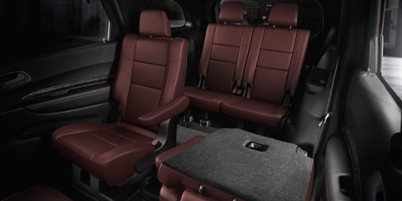 2026 Dodge Durango interior with red leather second-row captain's chairs, one folded forward, and the third-row bench, at Ross Downing CDJR of Mobile, AL