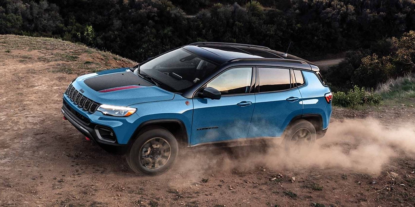 Blue 2026 Jeep Compass Trailhawk kicking up dust on a dirt hillside; Jeep Compass 4x4 capability explained by Ross Downing CDJR of Mobile, AL