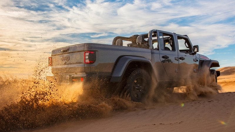 Gray 2026 Jeep Gladiator Mojave X kicking up sand in the desert; trade in your vehicle at Ross Downing CDJR of Mobile, AL