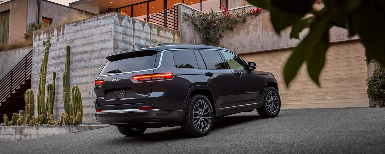 Black 2026 Jeep Grand Cherokee L Summit parked in the driveway of a modern home; new Grand Cherokee L SUVs for sale at Ross Downing CDJR of Mobile, AL