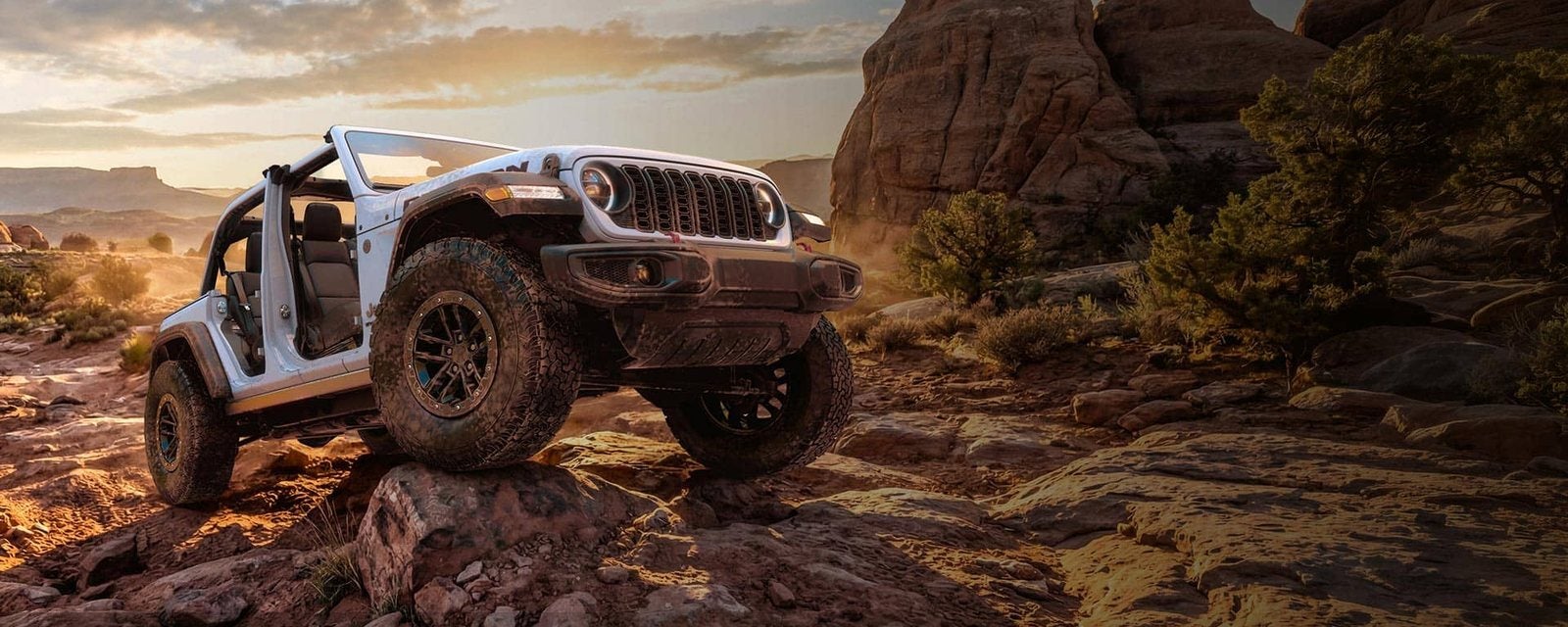 White 2026 Jeep Wrangler with the doors removed on a desert rock trail; new Wranglers for sale at Ross Downing CDJR of Mobile, AL