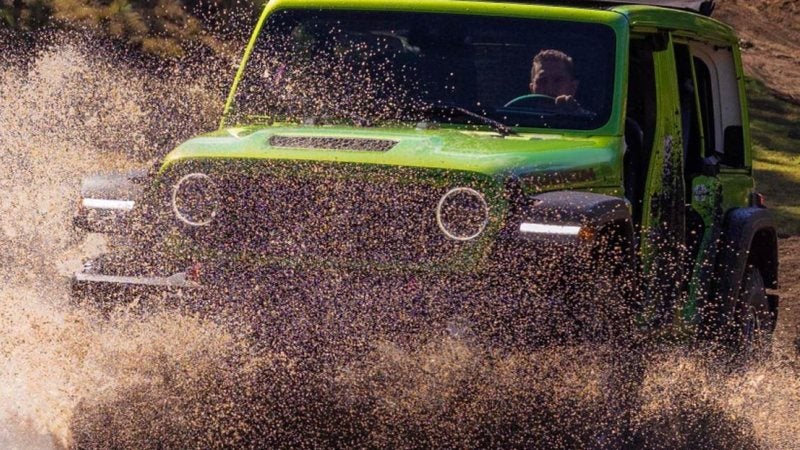 Green 2026 Jeep Wrangler Rubicon splashing through water; Jeep offers at Ross Downing CDJR of Mobile, AL